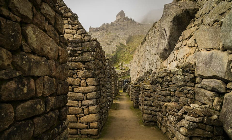 A breathtaking view of Machu Picchu surrounded by ruins on a cloudy day | Peruvian Sunrise