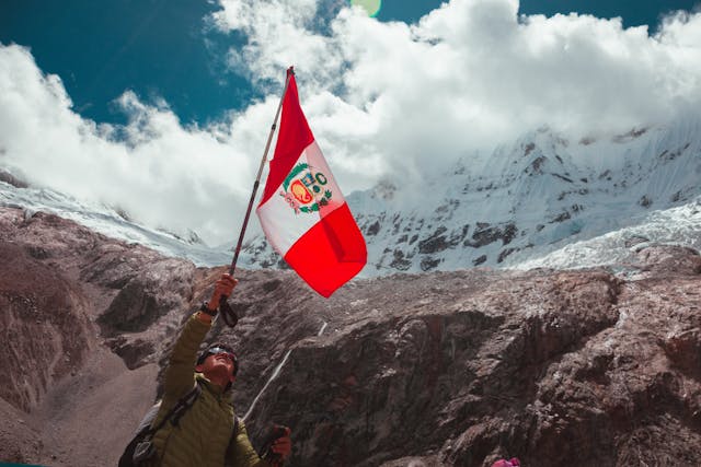 Peruvian flag held high in a trek to lagoon 69 in peru| Peruvian Sunrise