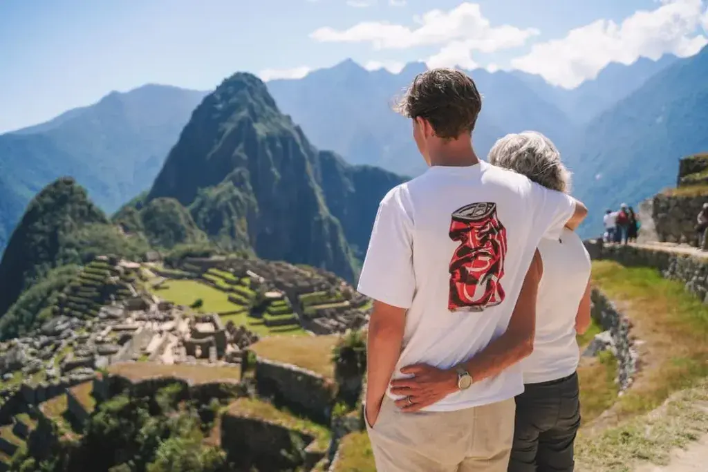 A breathtaking view of the iconic Machu Picchu ruins, surrounded by lush green mountains and tourists | Peruvian Sunrise